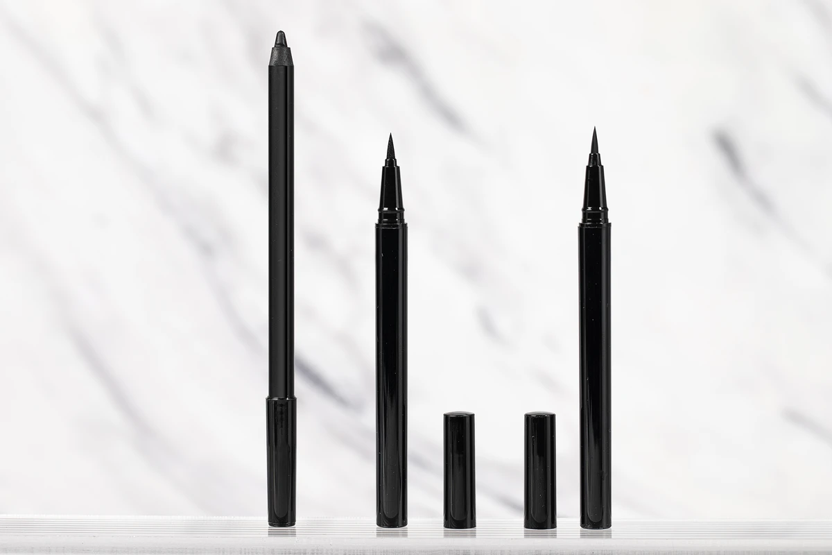 Close-up of 3 private label eyeliner pens with black barrels and varying tip sizes for precision, displayed on a white marble-patterned background.