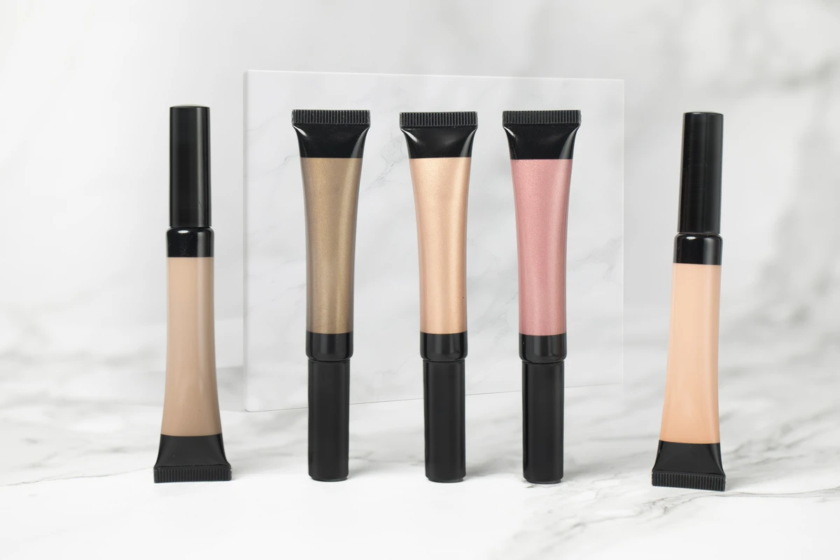 Close-up of 5 nude-tone long-lasting liquid eyeshadows with hydrating formula and glossy finish, displayed on a white marble-patterned background